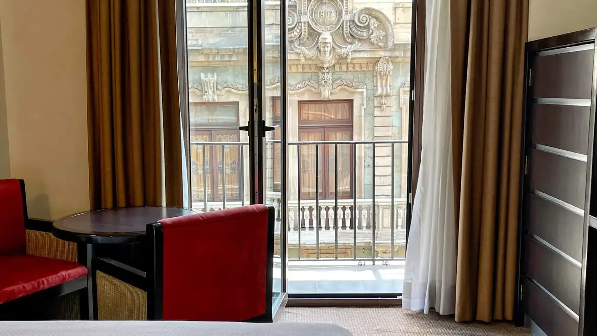 Hotel Catedral 객실 전망. 침대가 중앙에 있고 의자가 보입니다. 배경에 대성당이 보입니다.